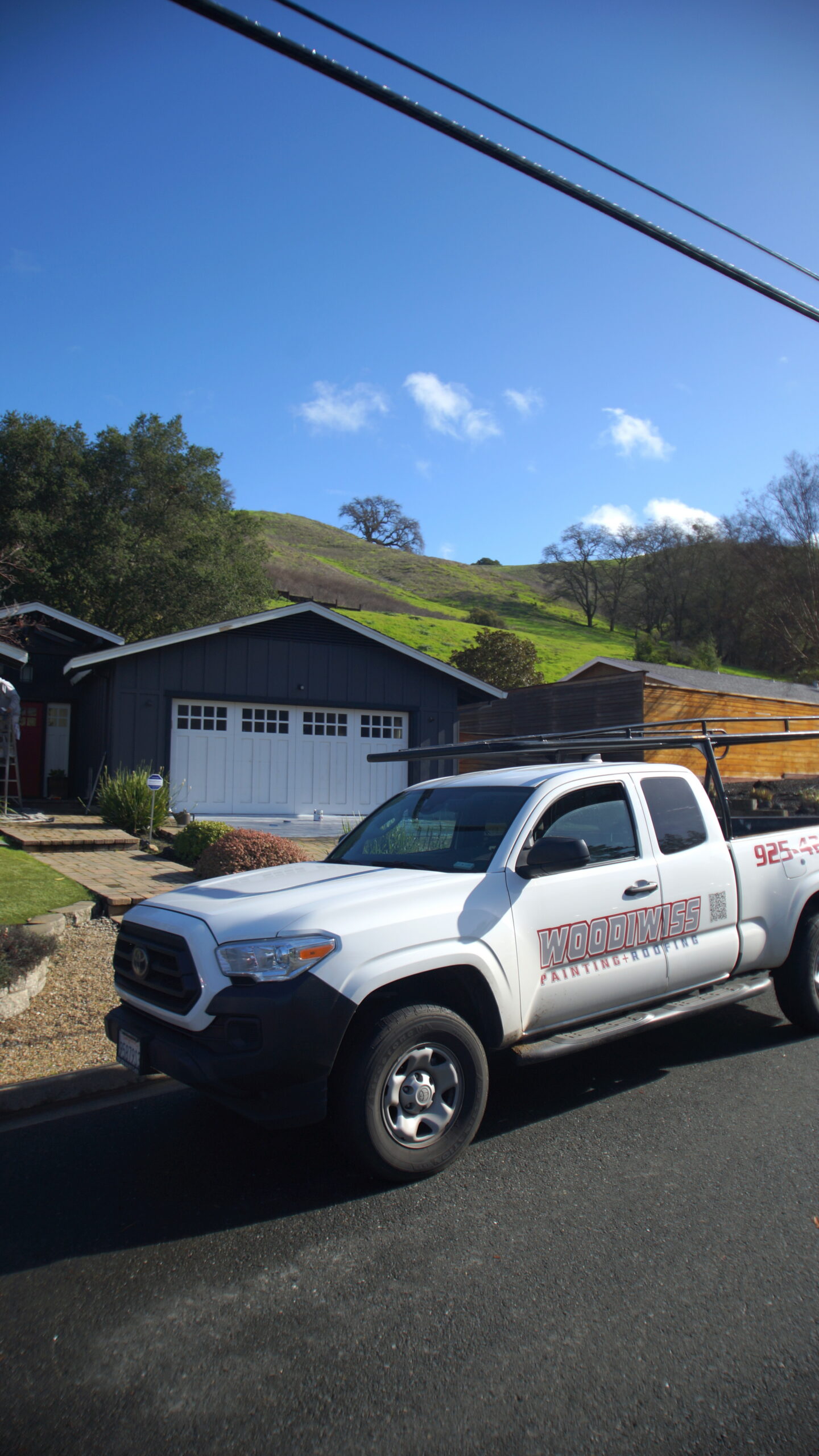 Woodiwiss Painting and Roofing Company Truck at a Residential Job Site White Woodiwiss Painting and Roofing truck parked at a residential property with a newly painted dark gray house.