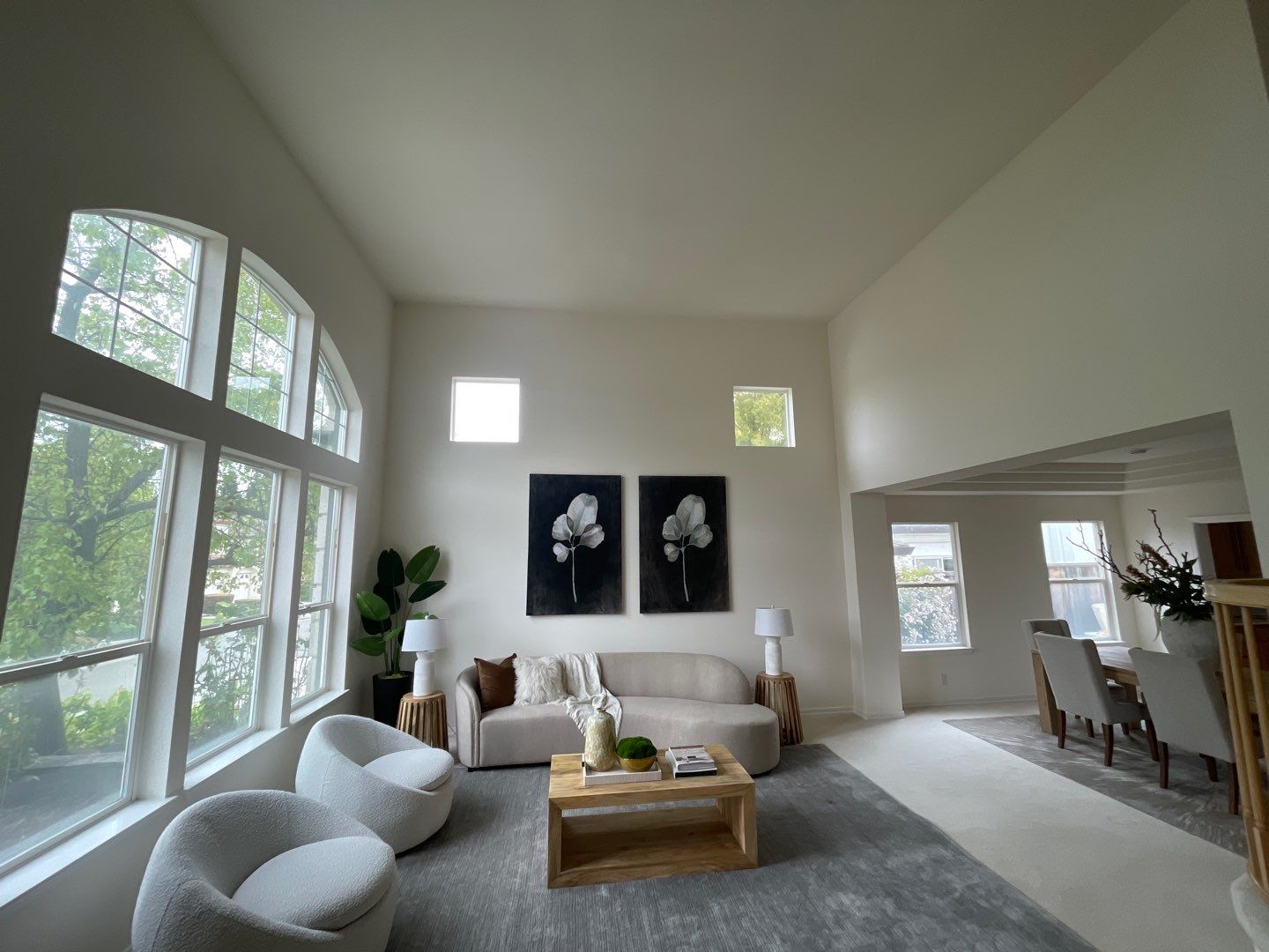 Soft Beige Interior Residential Living Room Soft beige-painted residential interior living room with vaulted ceiling, large windows, gray area rug, and neutral