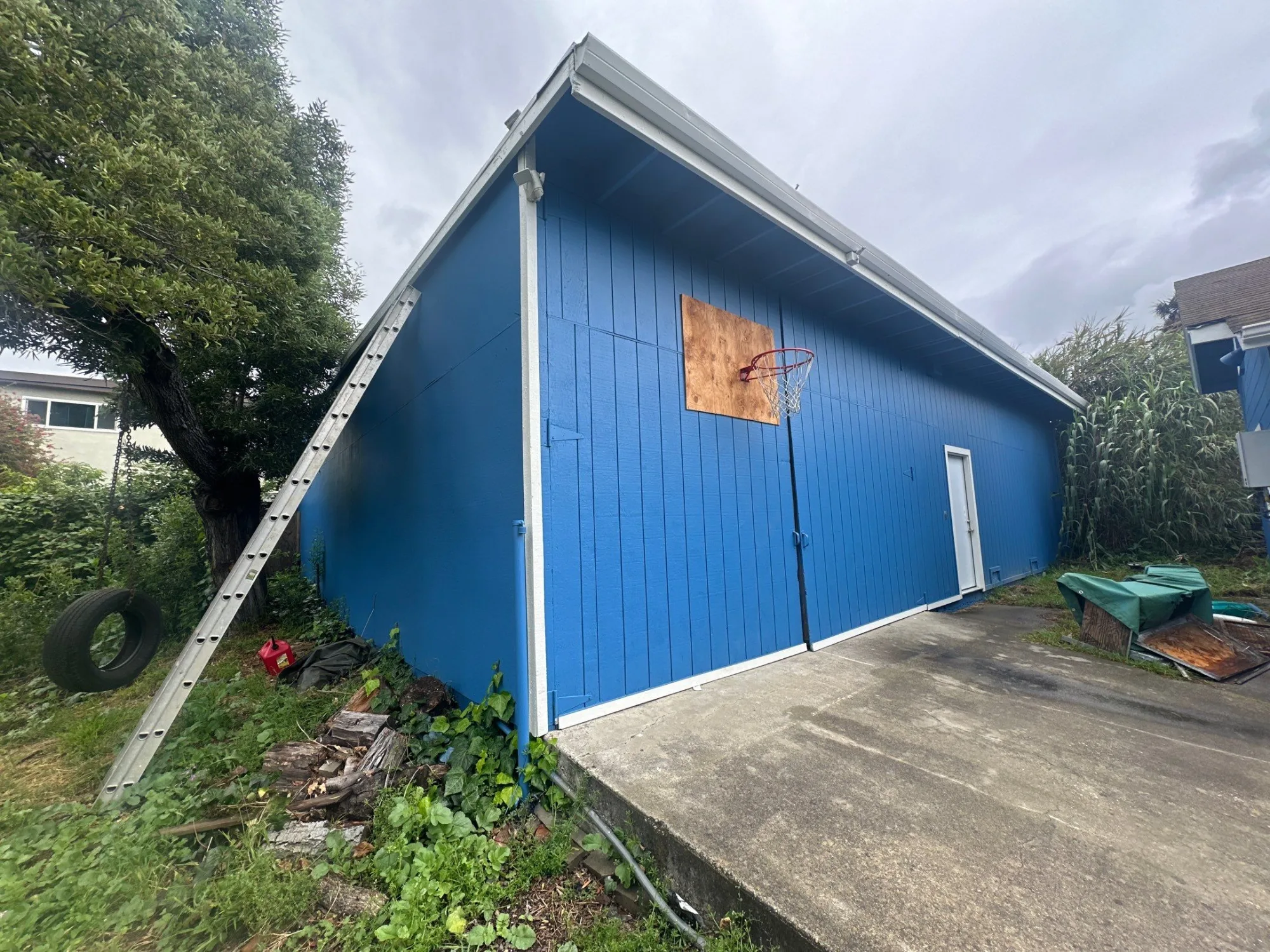 Bright Blue Garage Exterior Bright blue painted garage with white trim and metal garage doors after exterior residential painting